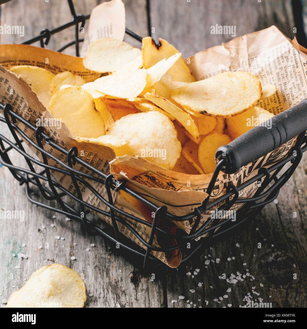 Basket with potato chips with sea salt over old wooden table. Square image with selective focus Stock Photo