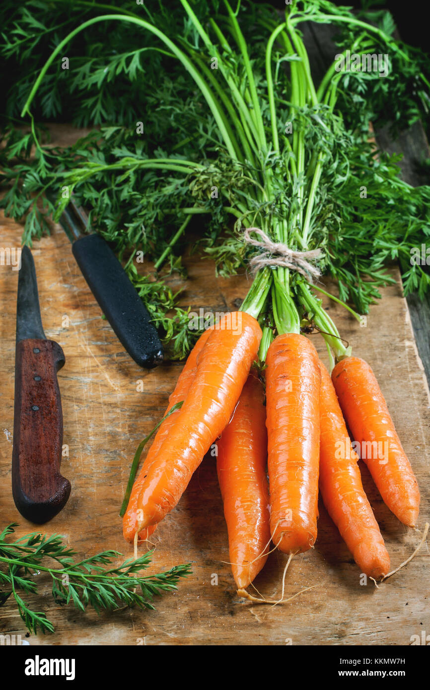 Bunch of fresh carrot with vintage knife on old cutting board. Stock Photo