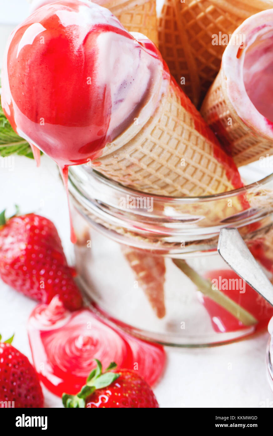 Close up of wafer cones with strawberry ice cream with syrup and fresh ...
