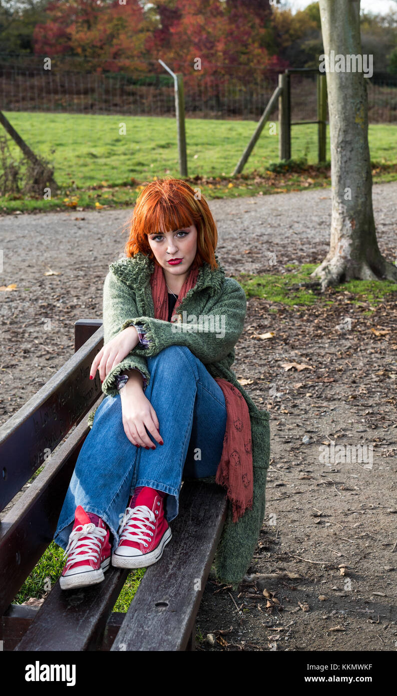 Girl on bench in park in autumn Stock Photo
