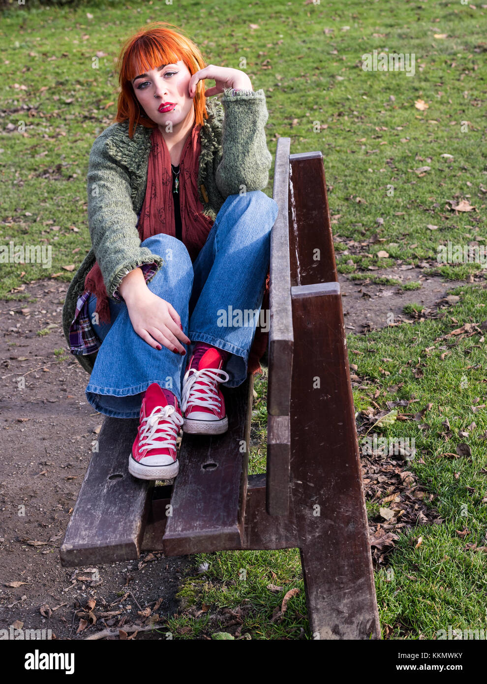 Redhead Girl on bench in park in autumn Stock Photo