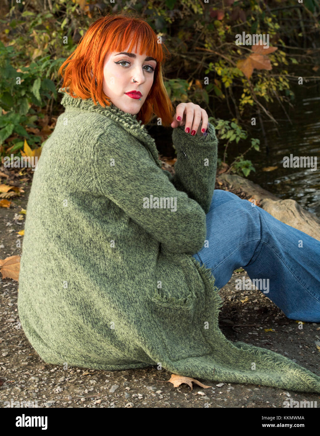 Beautiful redhead girl in park beside lake in fall Stock Photo