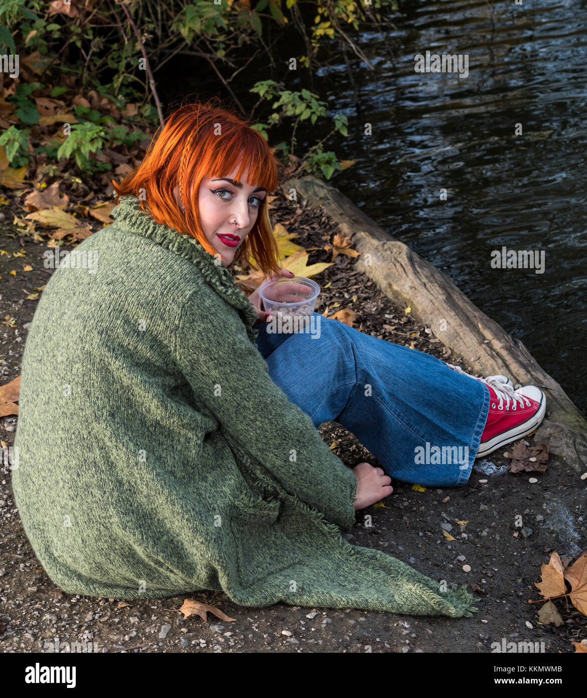 Beautiful redhead girl in park feeding ducks in fall Stock Photo
