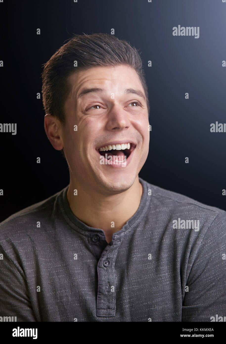 Laughing young man looking up, vertical portrait Stock Photo