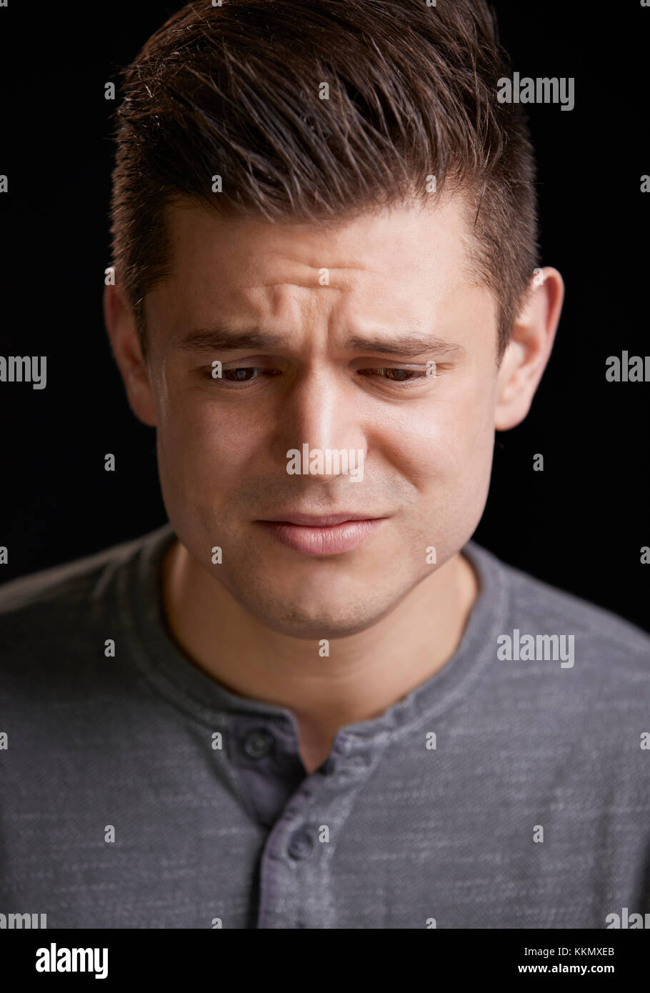 Worried young white man looking down, vertical portrait Stock Photo