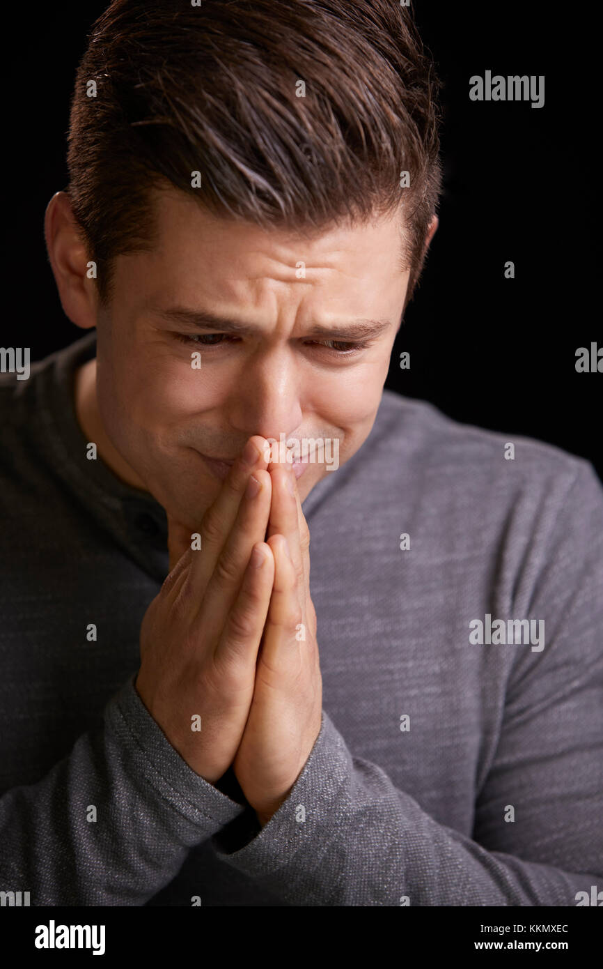 Worried young man with hands clasped, vertical portrait Stock Photo