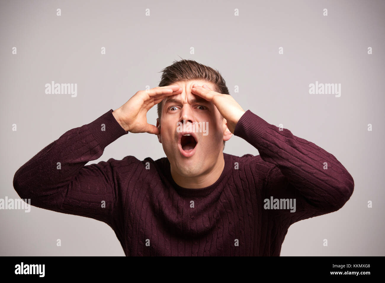Shocked young white man with hands by his head in disbelief Stock Photo