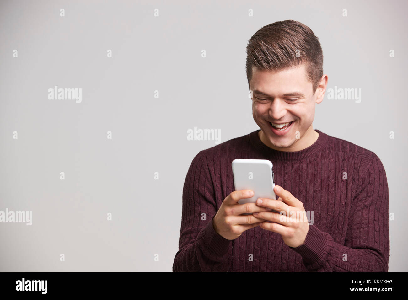 Portrait of a laughing young white man using a smartphone Stock Photo
