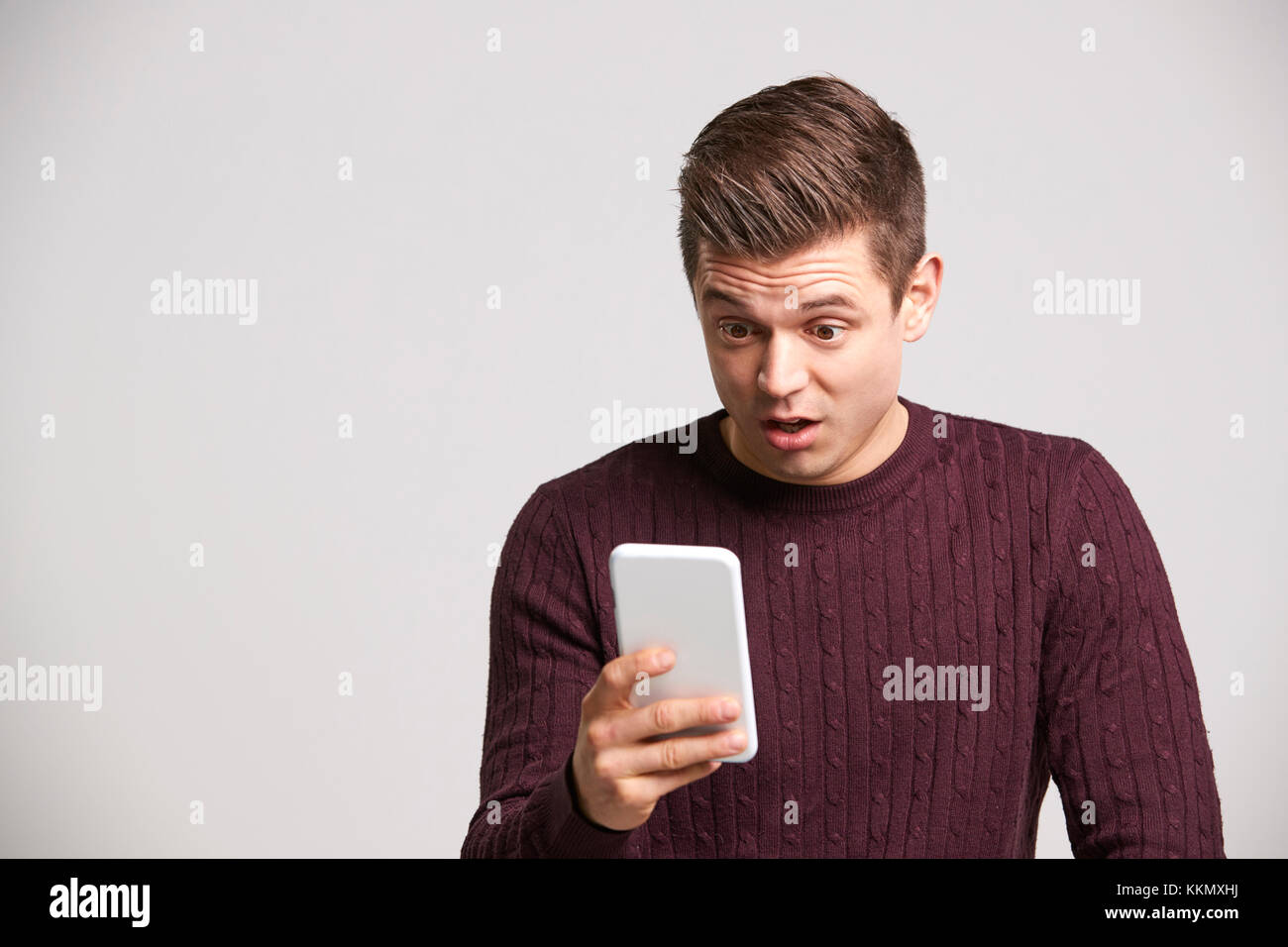 Portrait of a shocked young white man using a smartphone Stock Photo