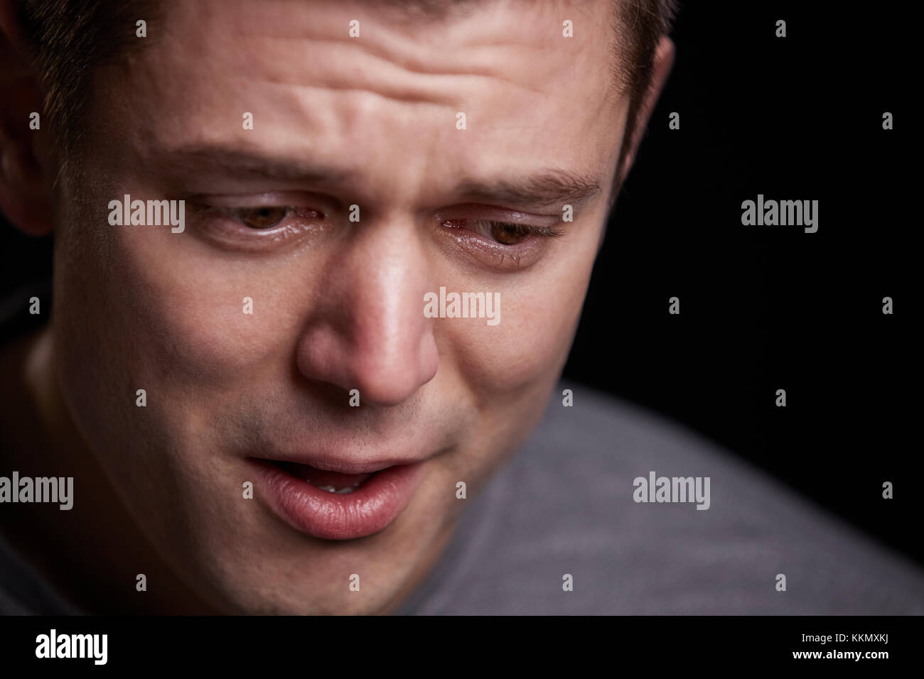Close up portrait of crying young white man looking down Stock Photo