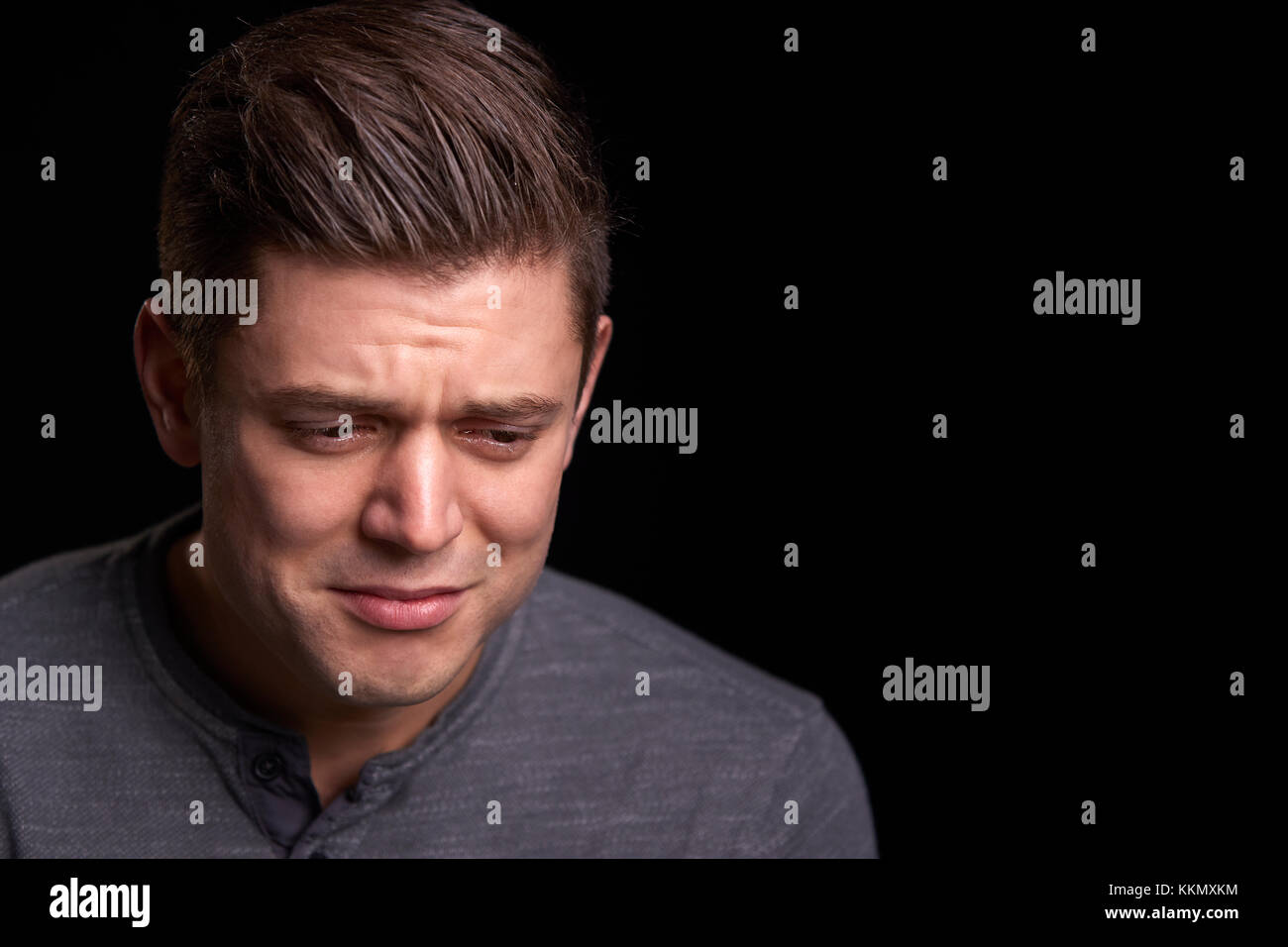 Portrait of crying young white man looking down Stock Photo