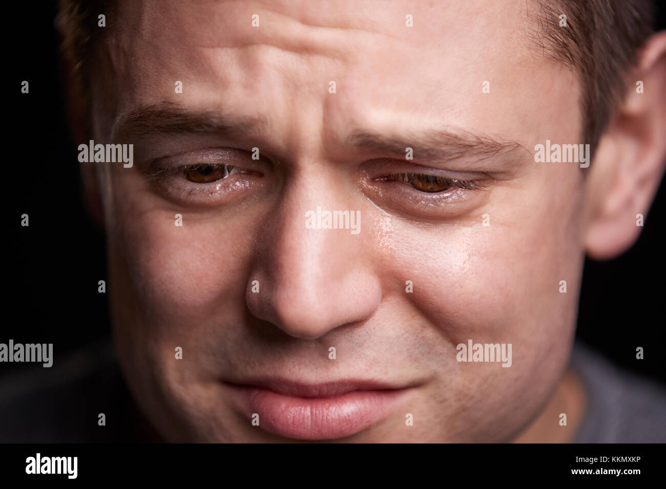 Close up portrait of crying young white man looking down Stock Photo