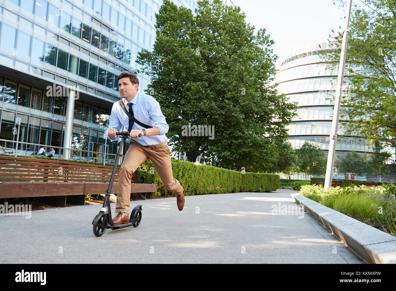Young Businessman Commuting To Work Through City On Scooter Stock Photo