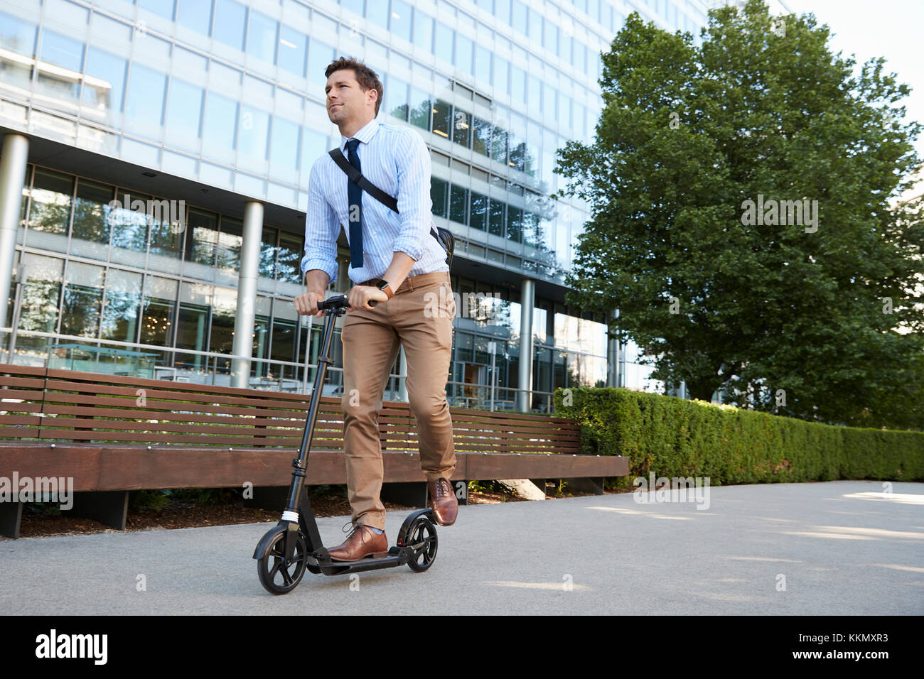Young Businessman Commuting To Work Through City On Scooter Stock Photo