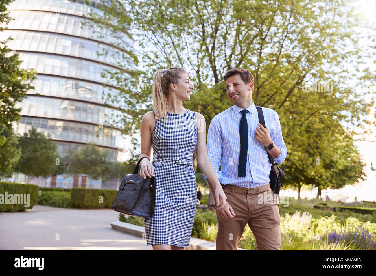 Businessman And Businesswoman Walk to Work Through City Park Stock Photo