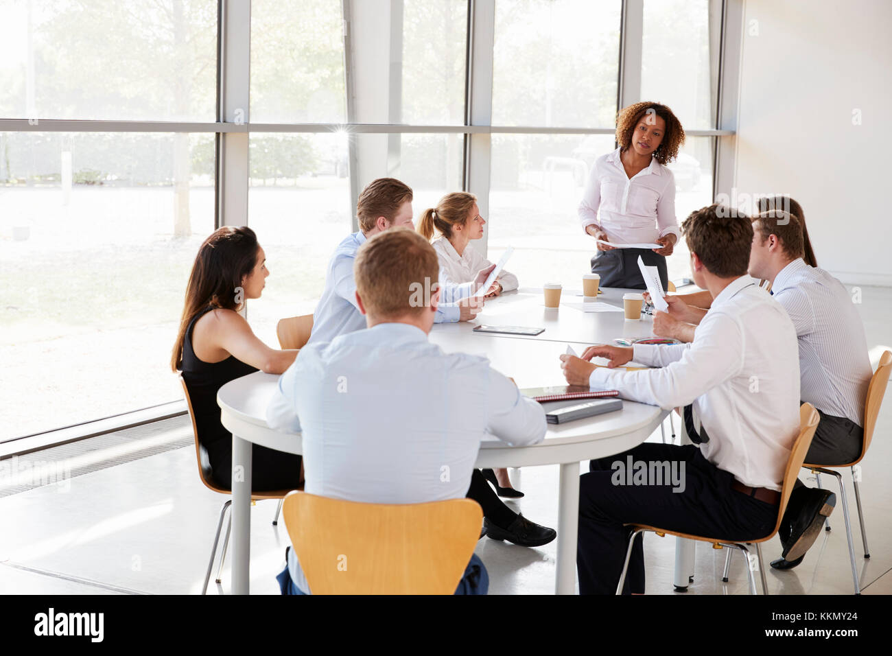 Businesswoman stands holding documents at a team meeting Stock Photo
