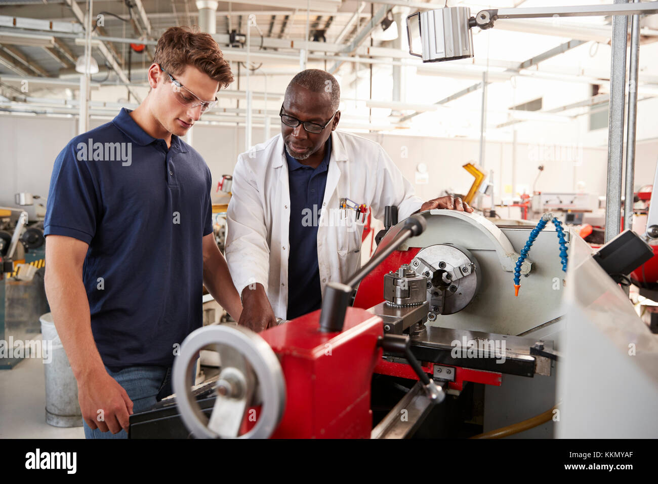 Engineer showing male apprentice how to operate machinery, close up