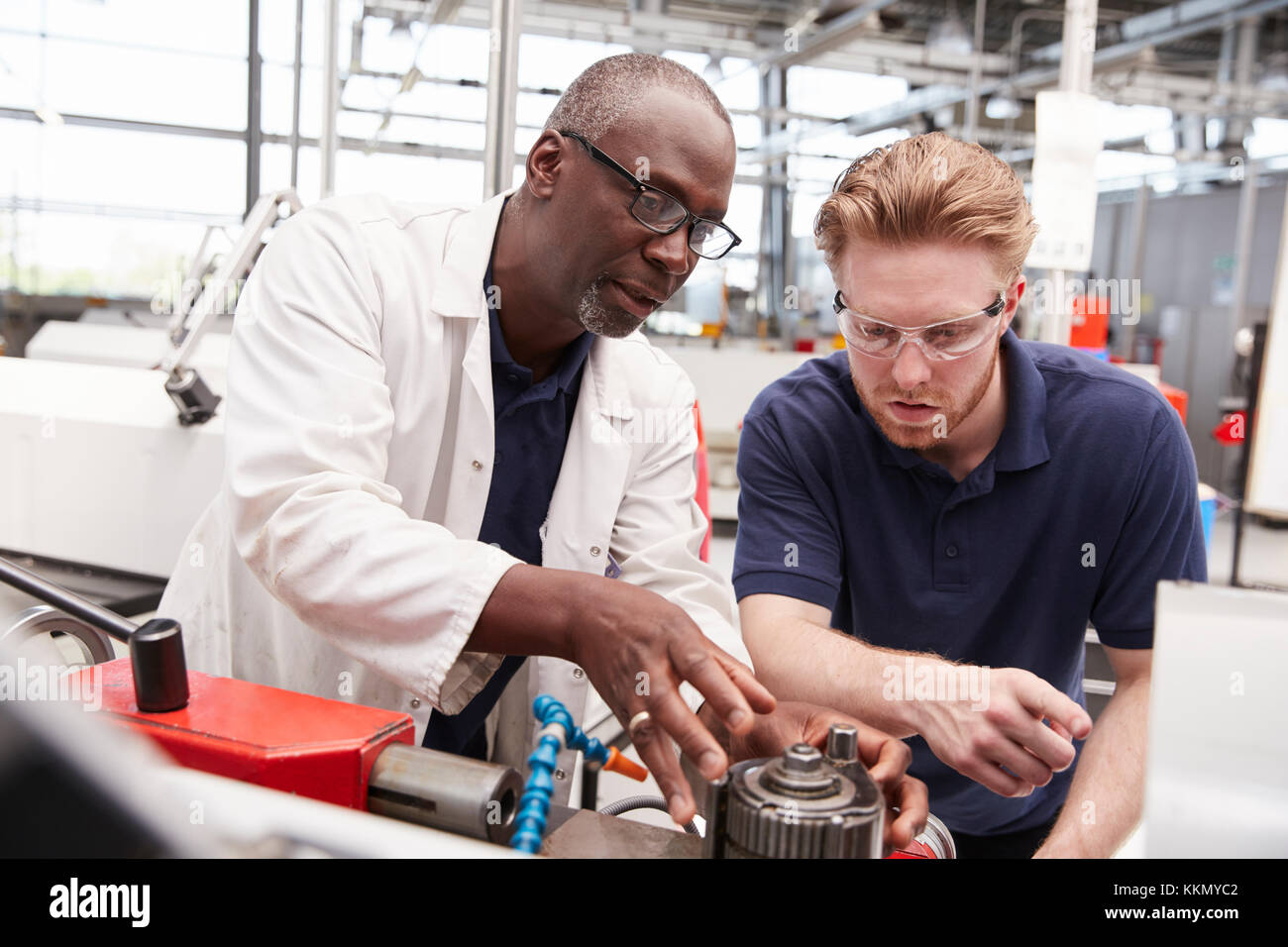 Engineer advising a male apprentice in a factory, close up Stock Photo