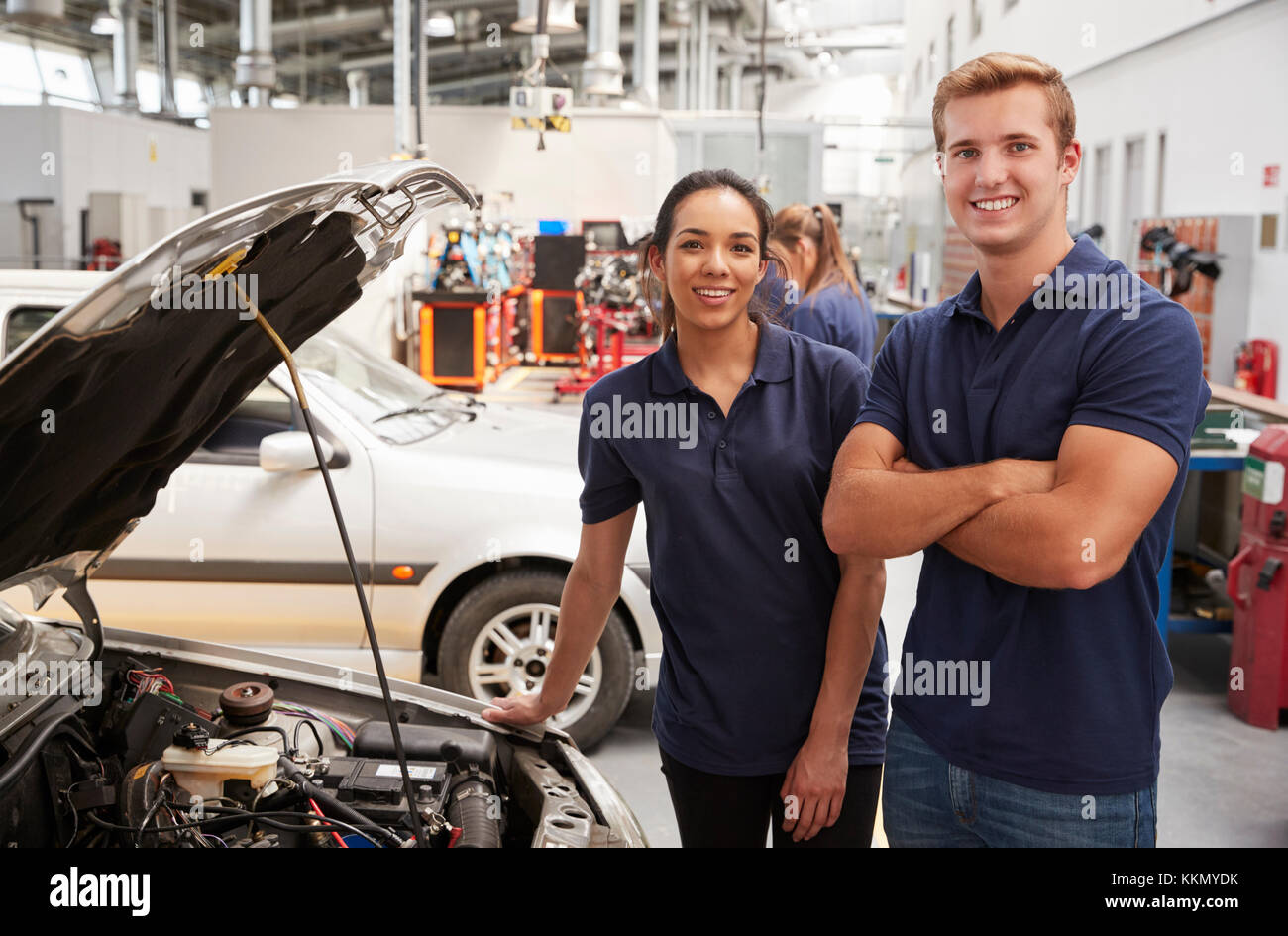 Two apprentice mechanics looking to camera beside a car Stock Photo - Alamy