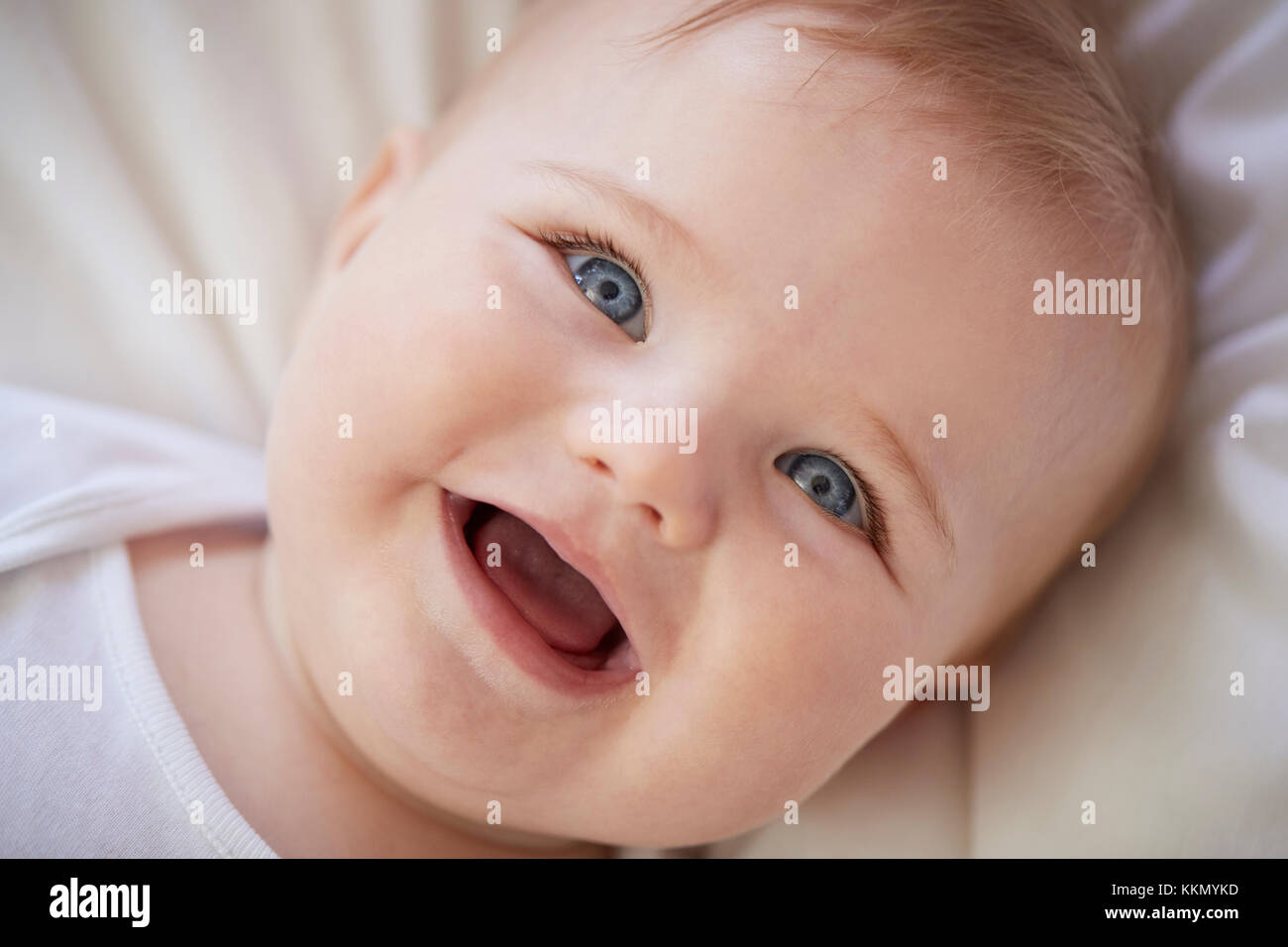 Overhead Shot Of Happy Baby Boy Lying On Parents Bed Stock Photo