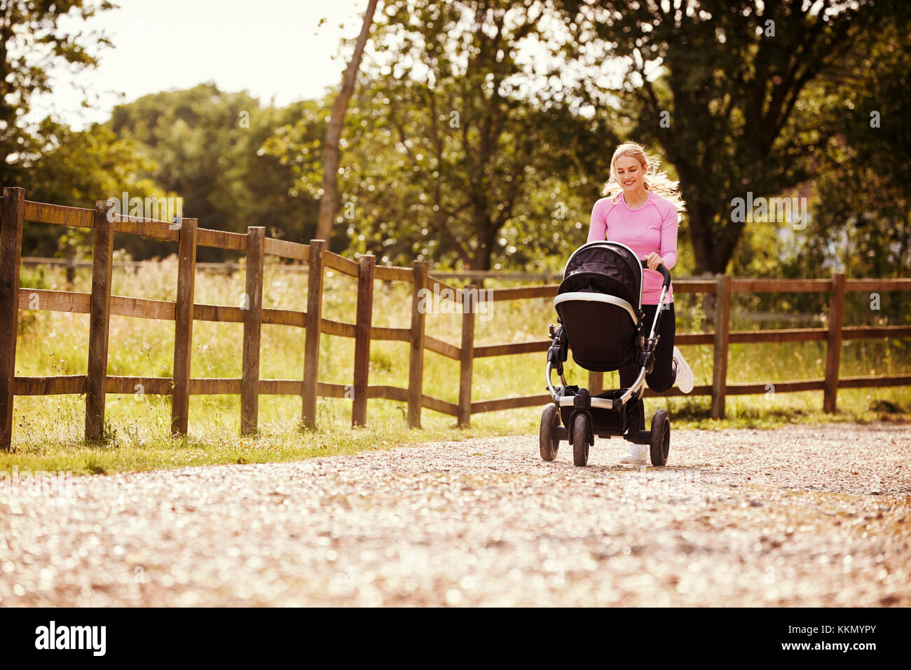 Mother Exercising By Running Whilst Pushing Baby Buggy Stock Photo