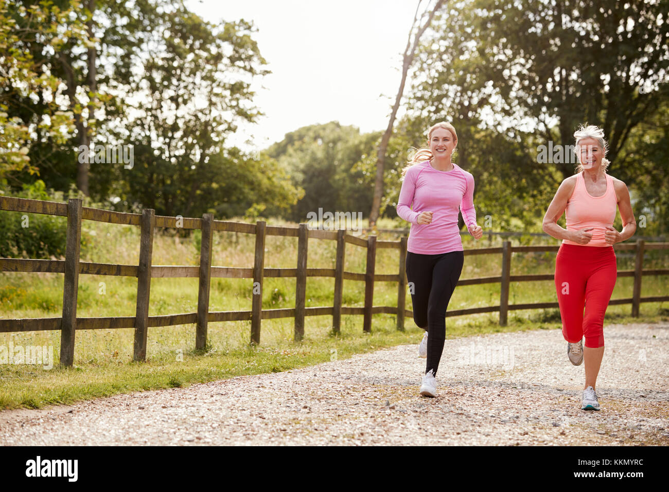 Young And Senior Women Enjoying Run Through Countryside Together Stock Photo