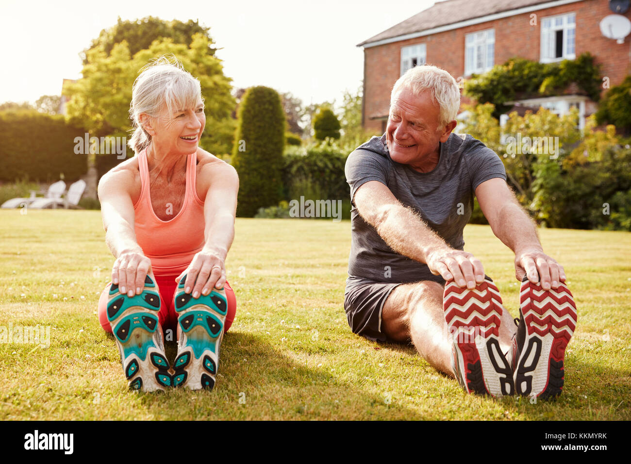 Healthy Senior Couple Exercising In Garden Together Stock Photo