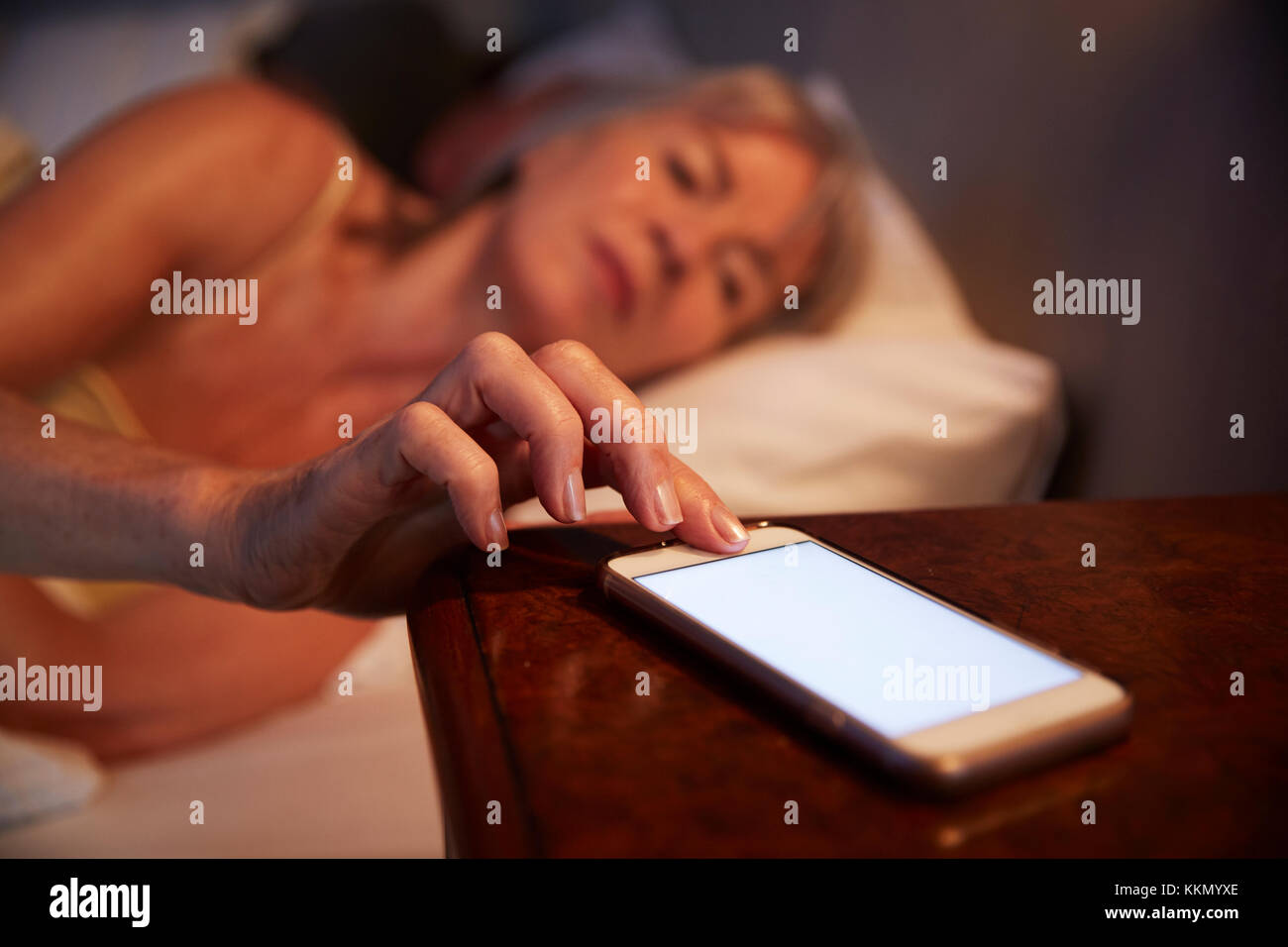 Sleepless Senior Woman In Bed At Night Checking Mobile Phone Stock Photo