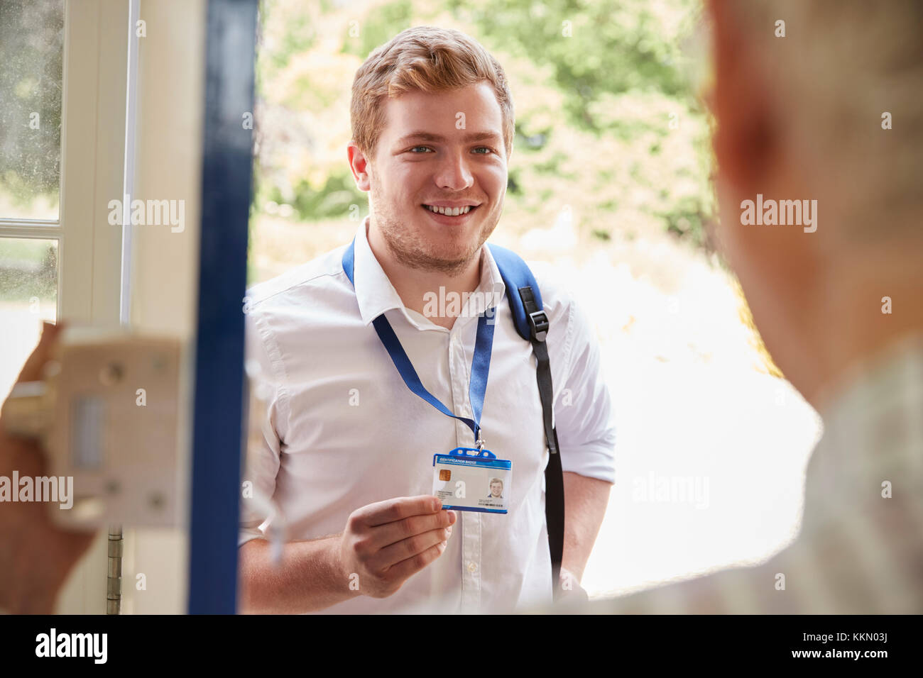 Male care worker showing ID to senior man at his front door Stock Photo