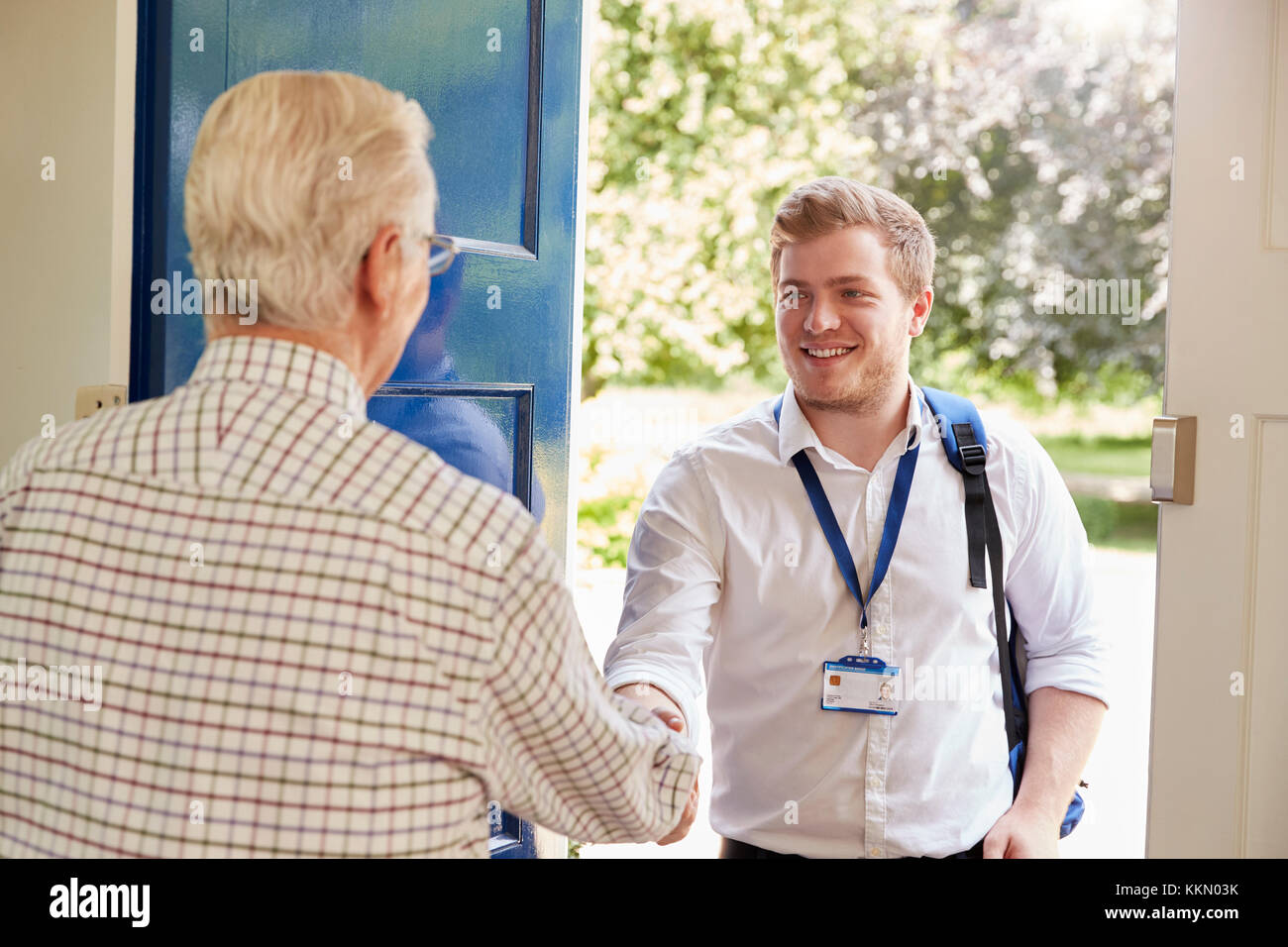 Senior man greeting male care worker making home visit Stock Photo