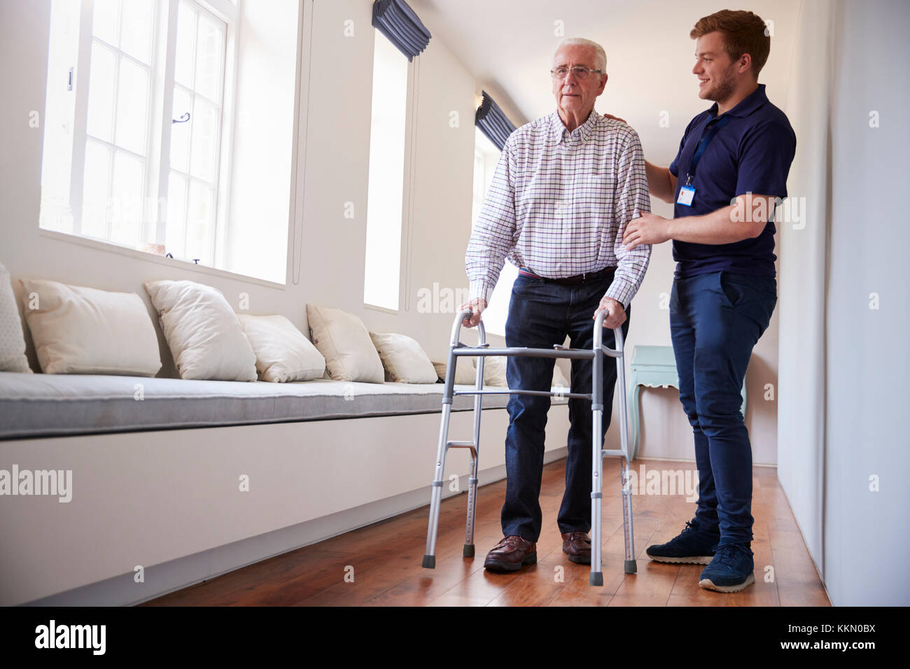 Senior man using a walking frame with male nurse at home Stock Photo