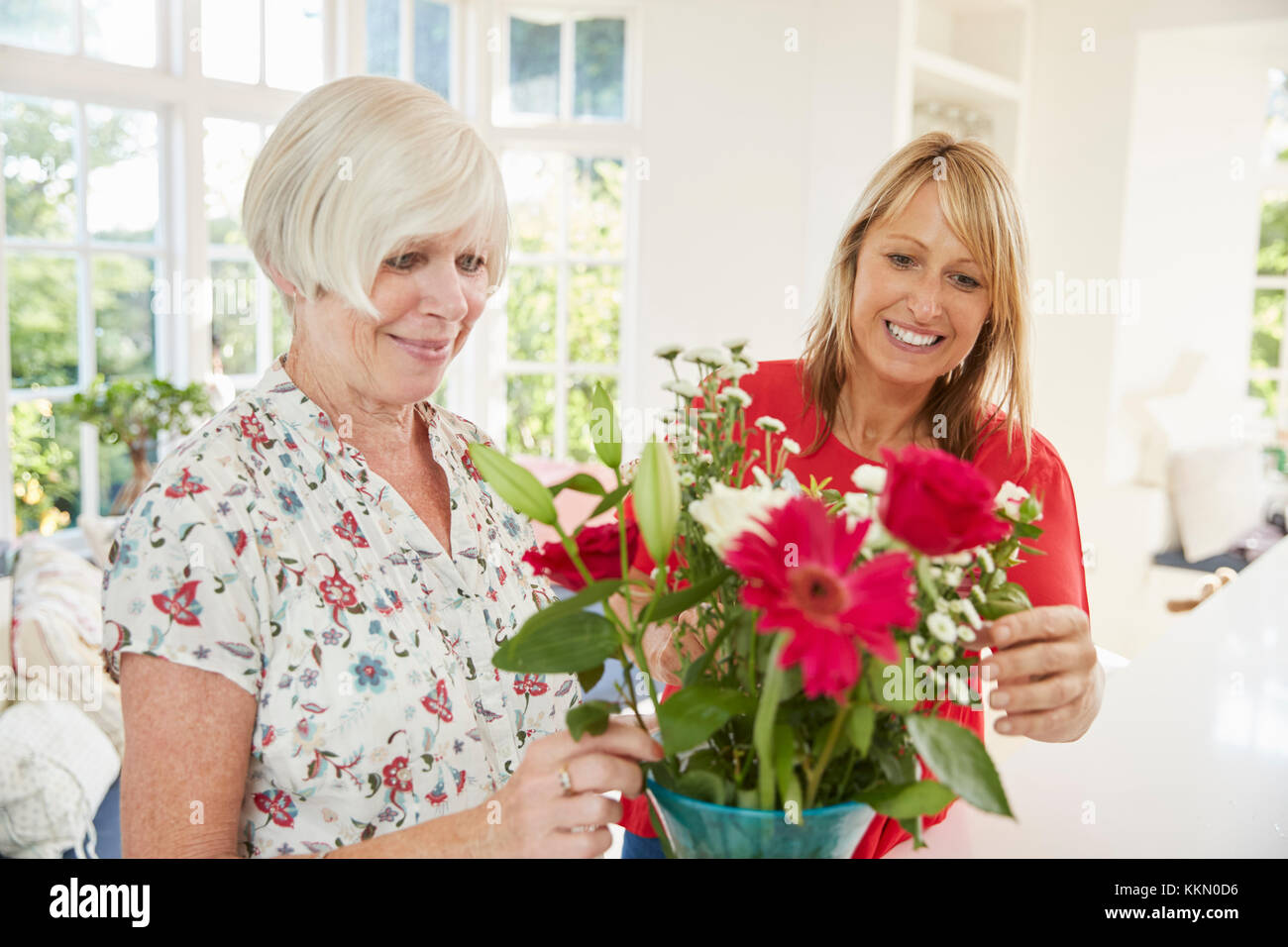 Senior woman and adult daughter arranging flowers at home Stock Photo