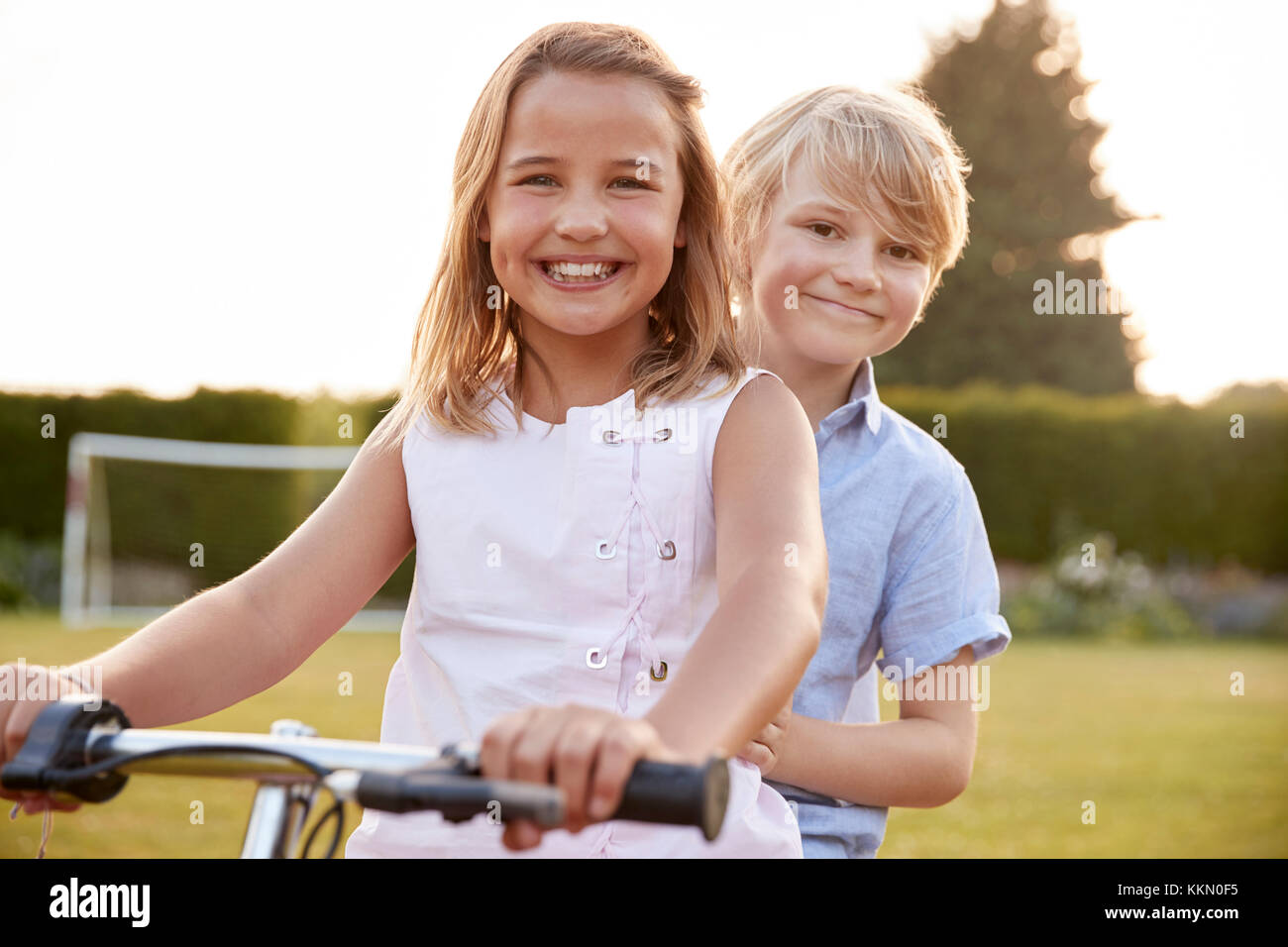 Two children riding a bicycle in the garden Stock Photo