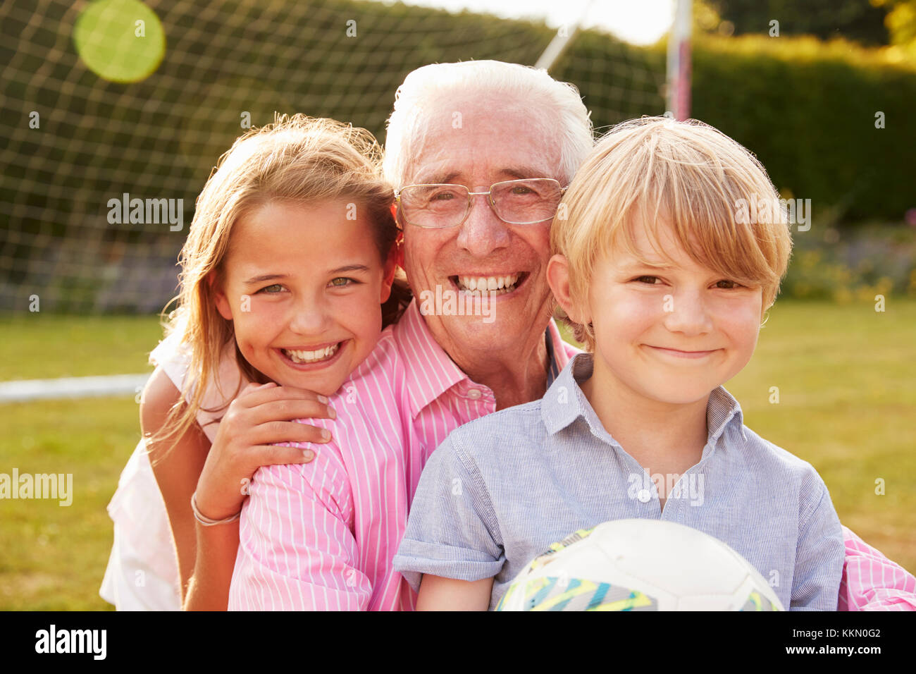 Senior man and grandchildren holding ball smiling to camera Stock Photo