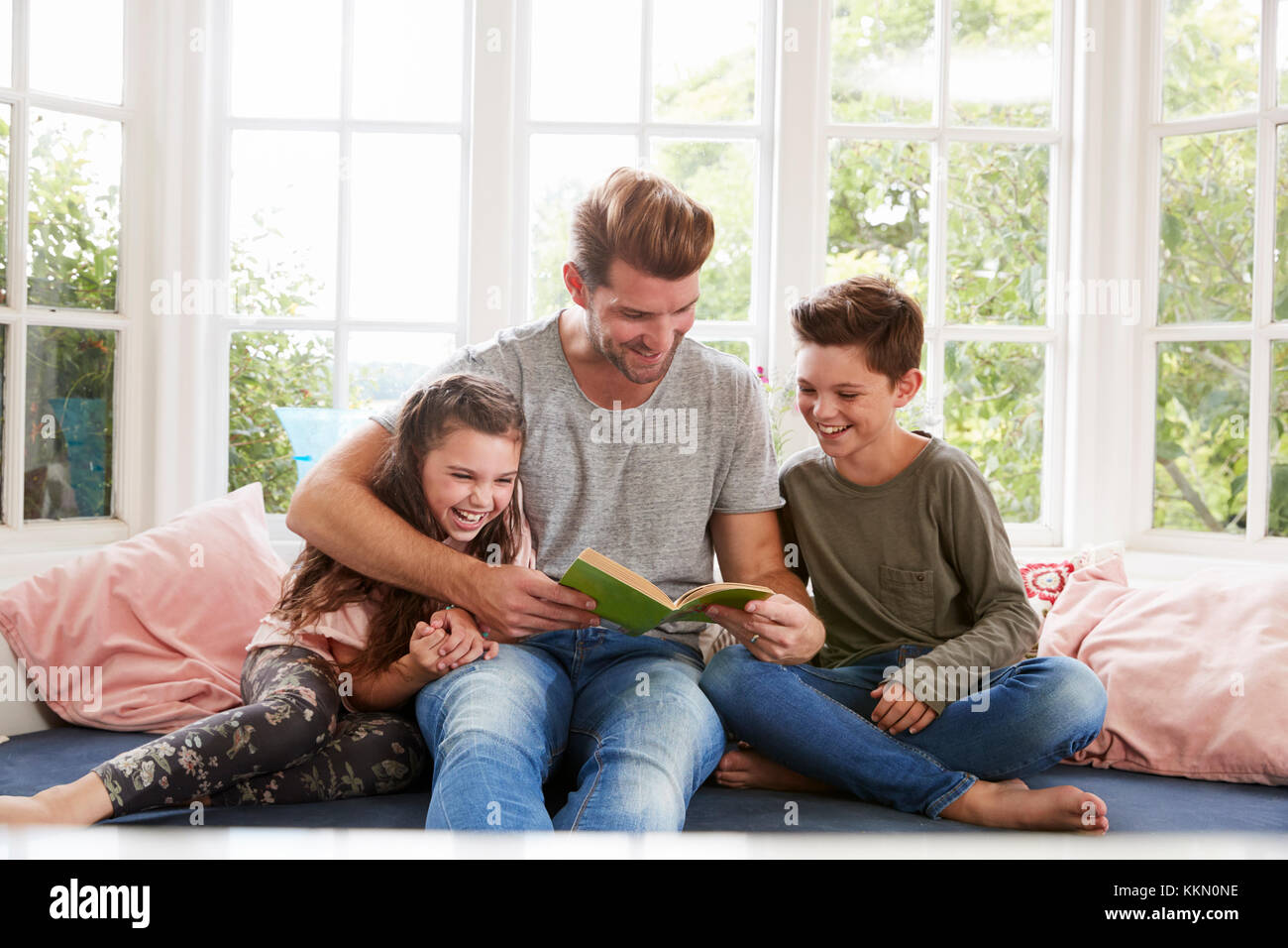 Father Reading Book With Son And Daughter At Home Stock Photo