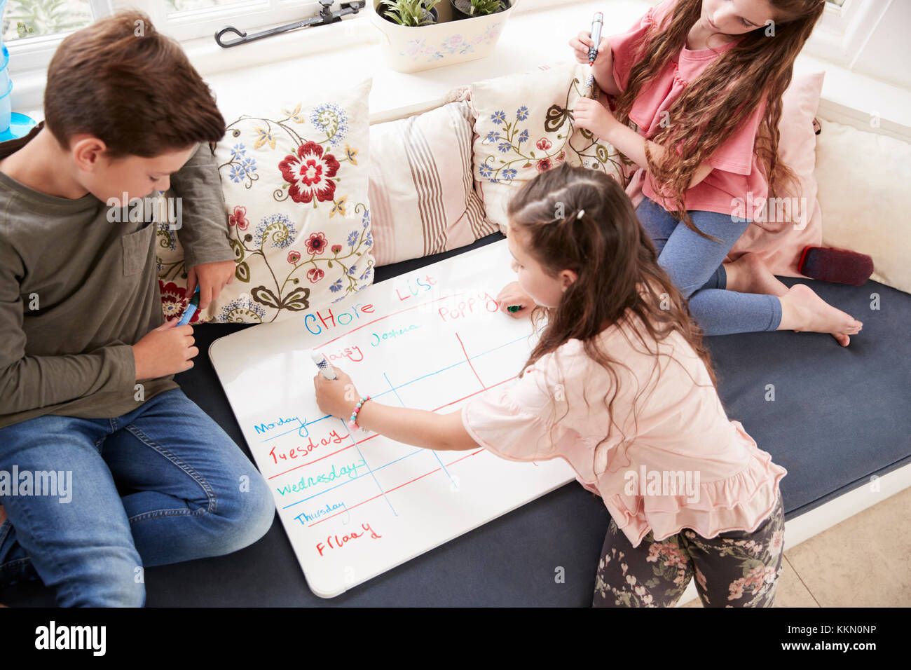 Children Making List Of Chores On Whiteboard At Home Stock Photo