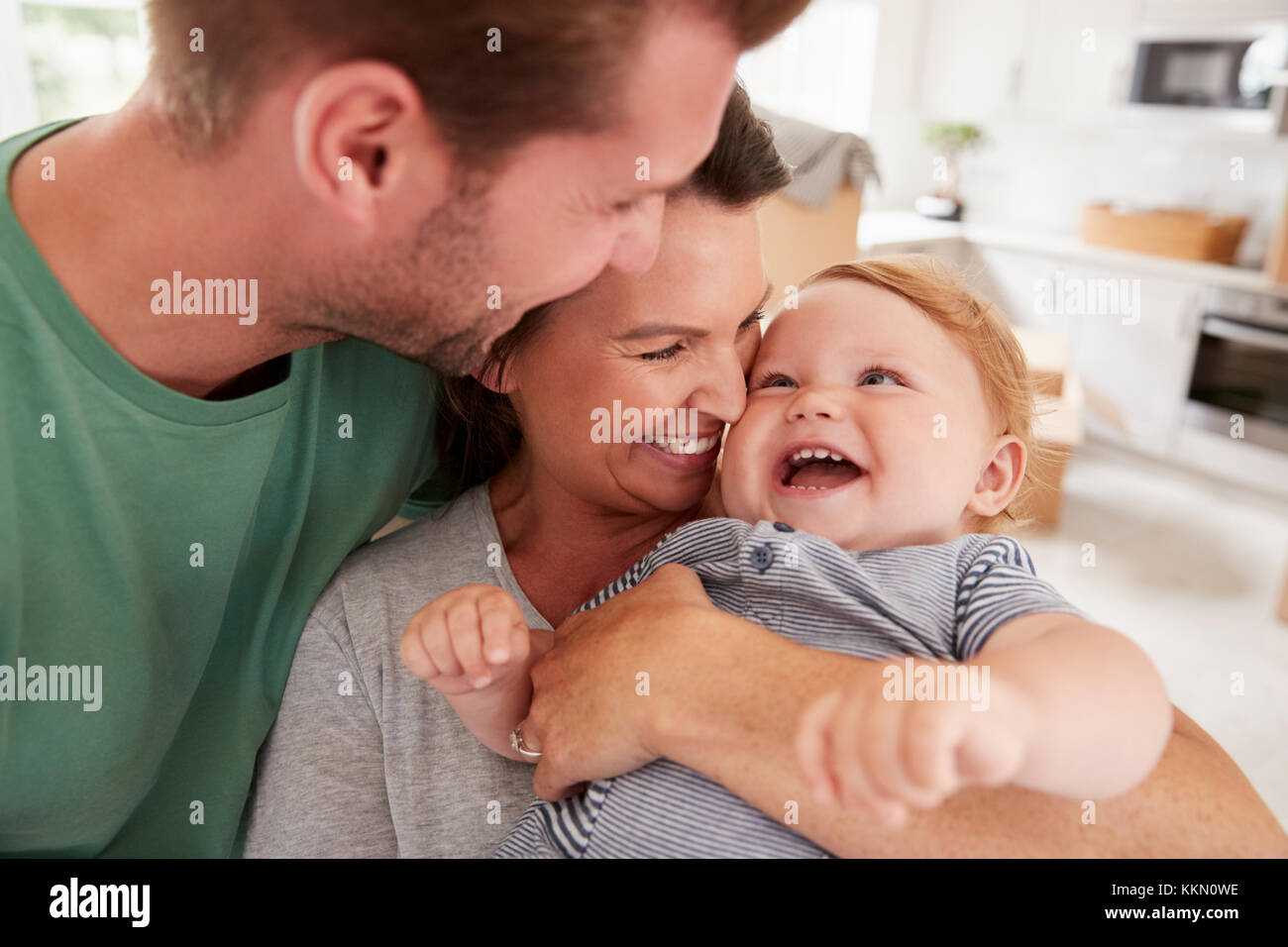 Close Up Of Parents Hugging Happy Baby Son At Home Stock Photo