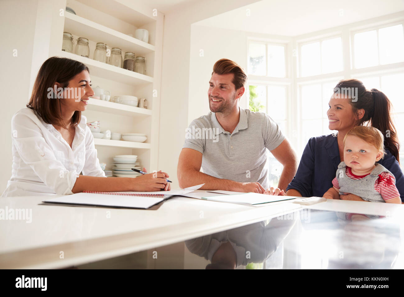 Family With Baby Meeting Financial Advisor At Home Stock Photo