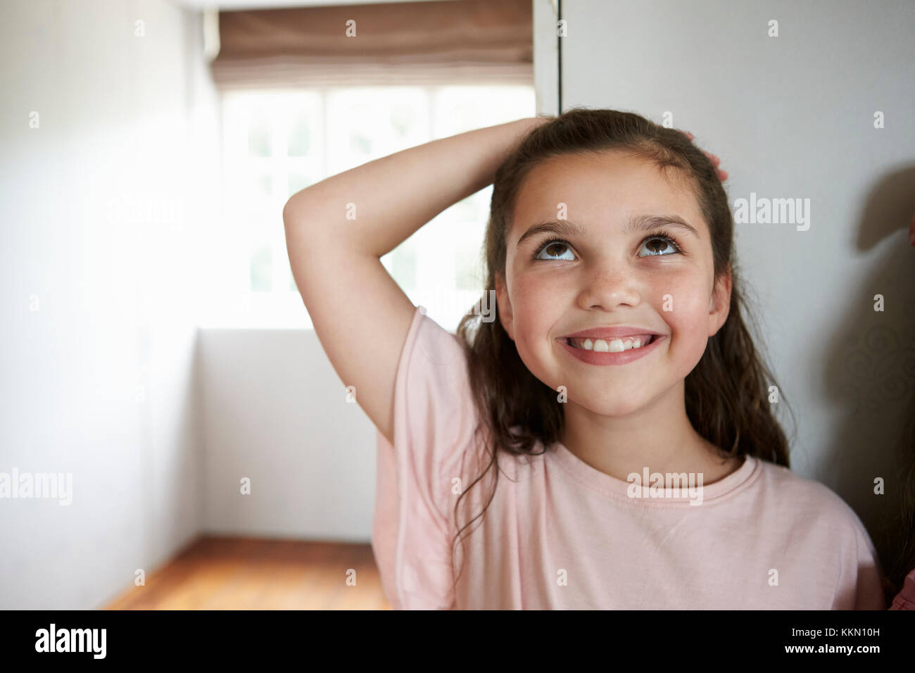 Girl Measuring Height Standing Against Wall At Home Stock Photo