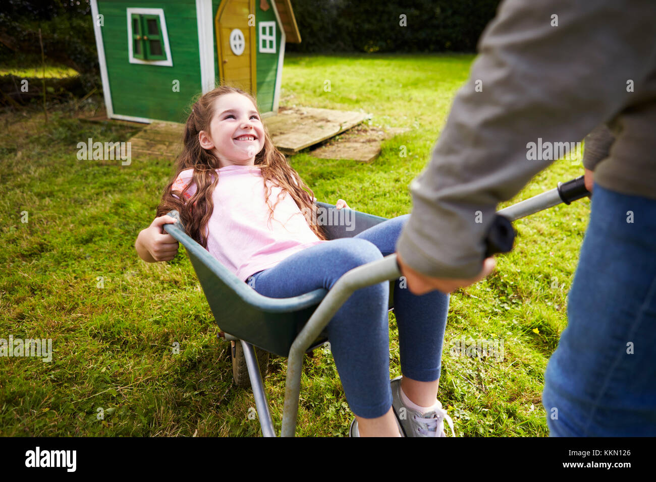 Brother Pushing Sister In Garden Wheelbarrow Stock Photo