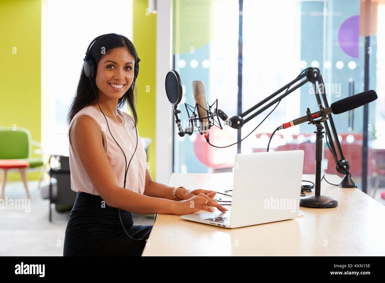 Young mixed race woman recording a podcast smiling to camera Stock Photo