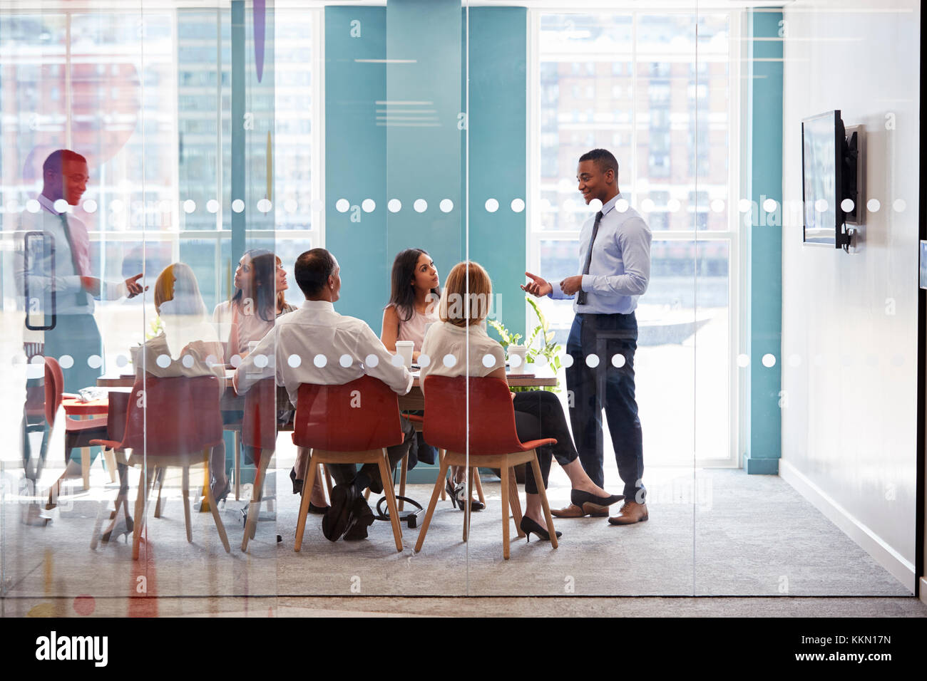 Young male boss stands addressing business team at meeting Stock Photo ...