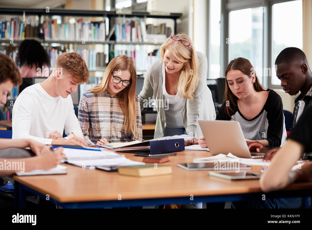 Female Teacher Working With College Students In Library Stock Photo Alamy