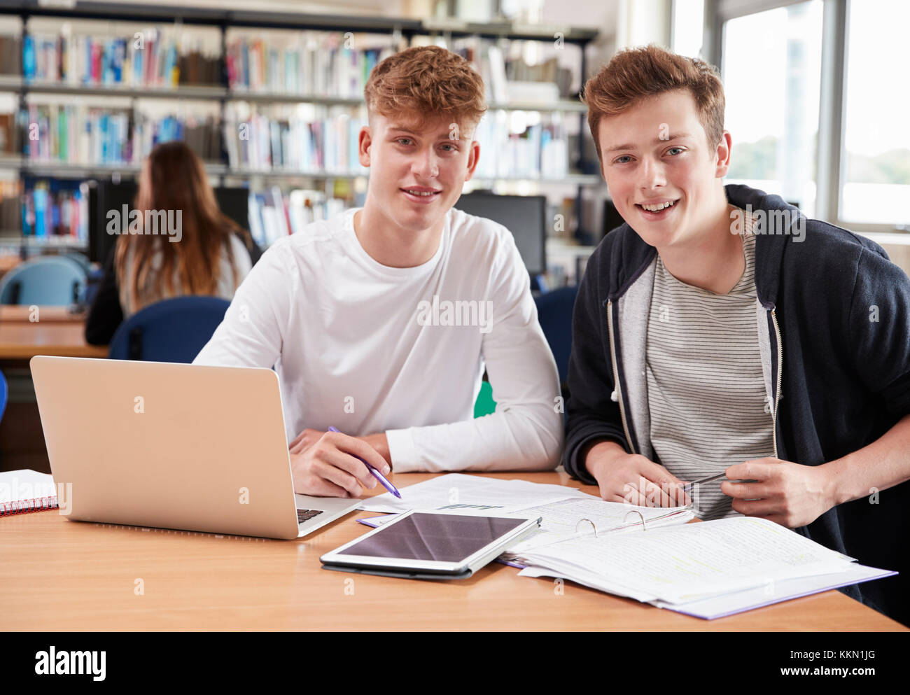 Two Male College Students Collaborating On Project In Library Stock Photo
