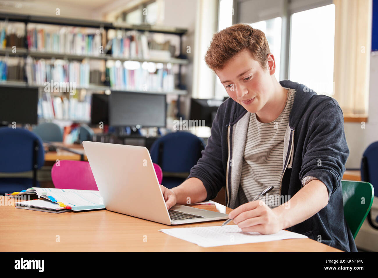 Male Student Working At Laptop In College Library Stock Photo