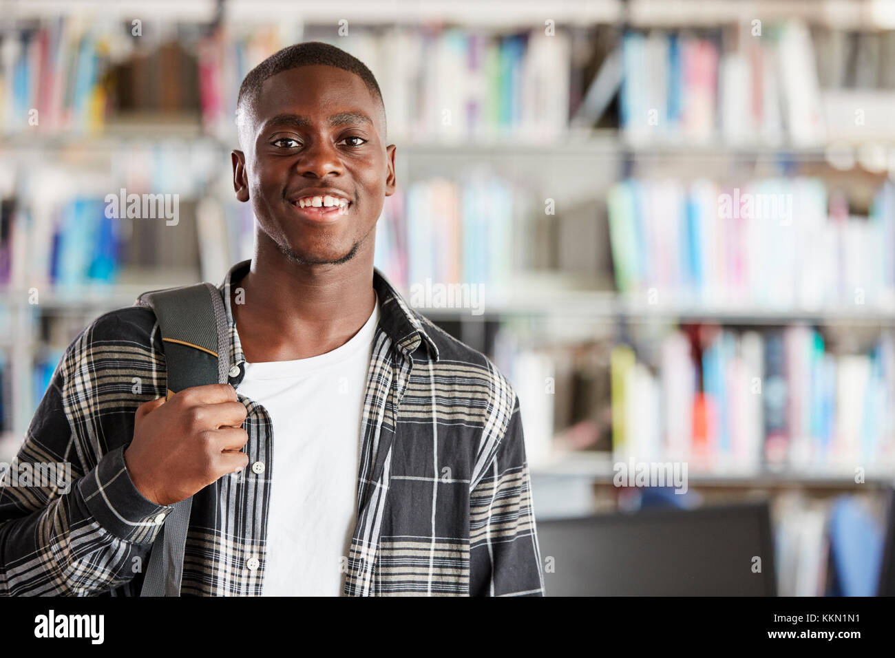 Portrait Of Male Student Standing In College Library Stock Photo