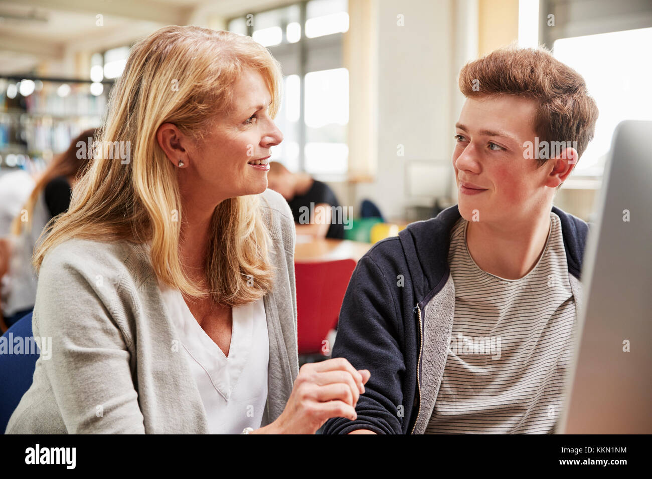 Teacher With Male Student Working On Computer In College Library Stock Photo