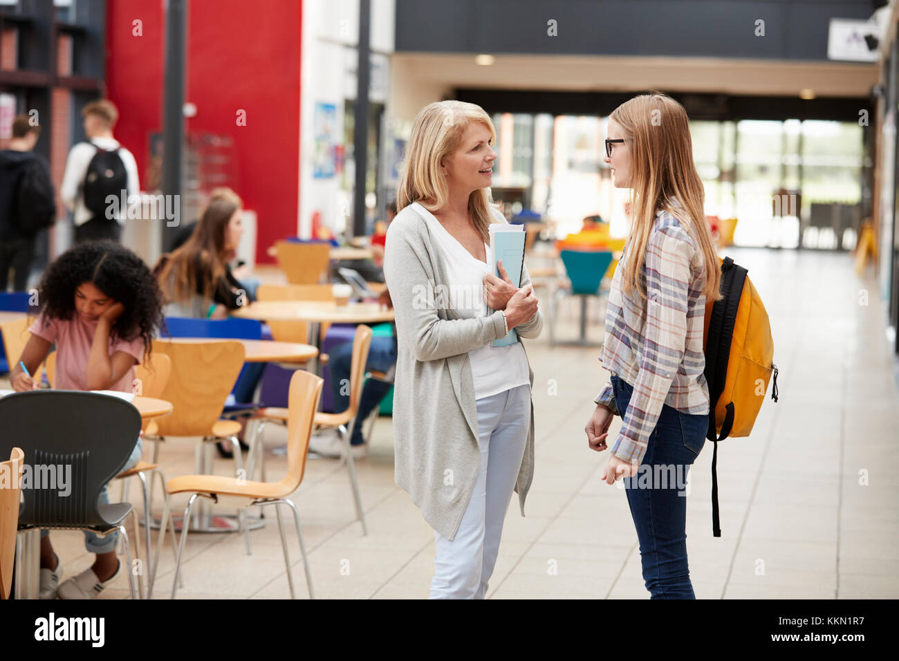 Teacher Talks To Student In Communal Area Of College Campus Stock Photo