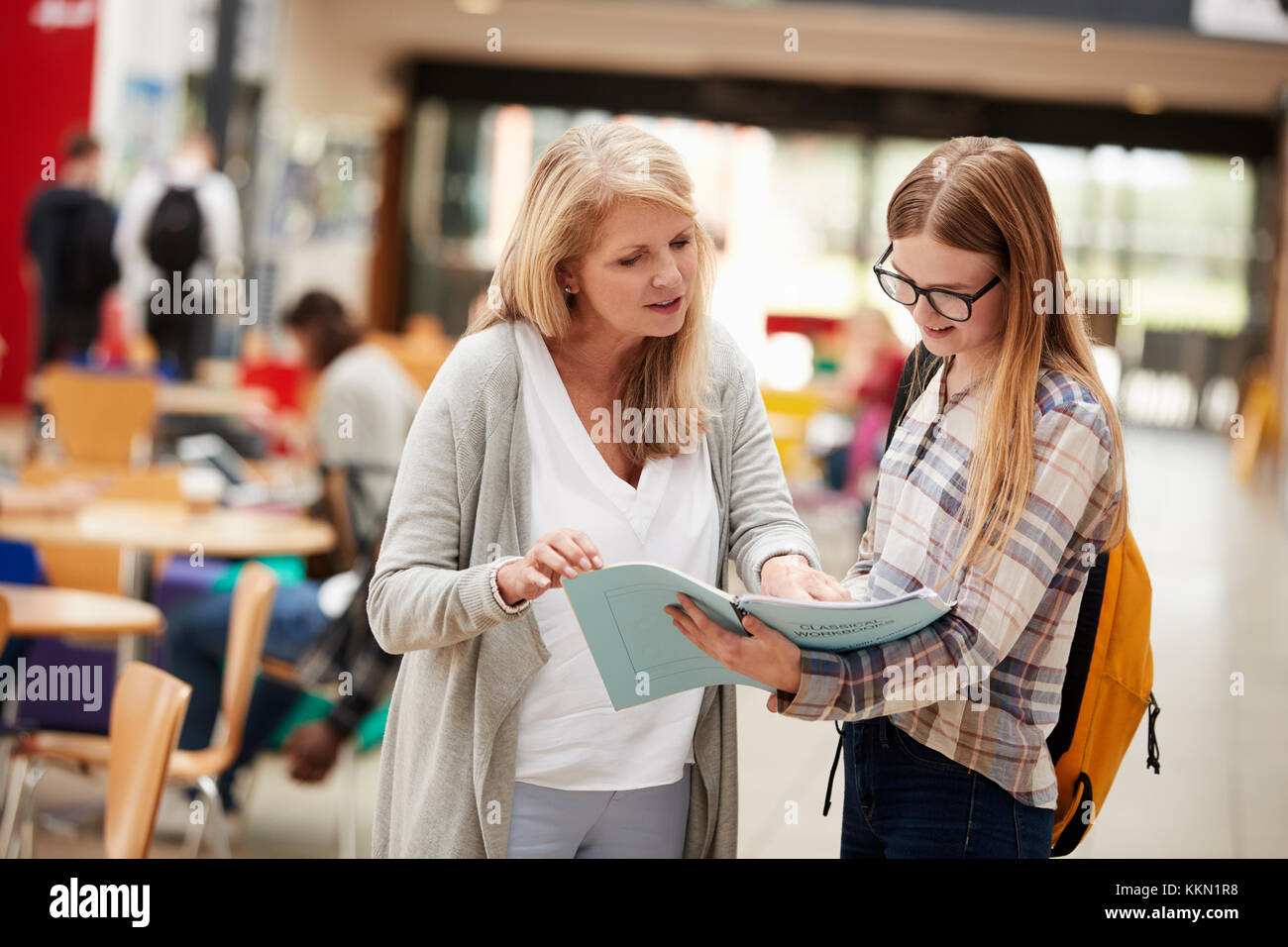 Teacher Talks To Student In Communal Area Of College Campus Stock Photo