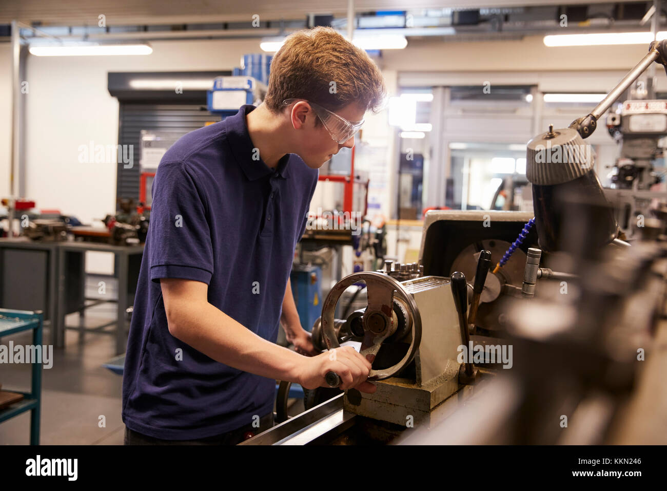Male Teenage Apprentice In Engineering Factory Using Lathe Stock Photo